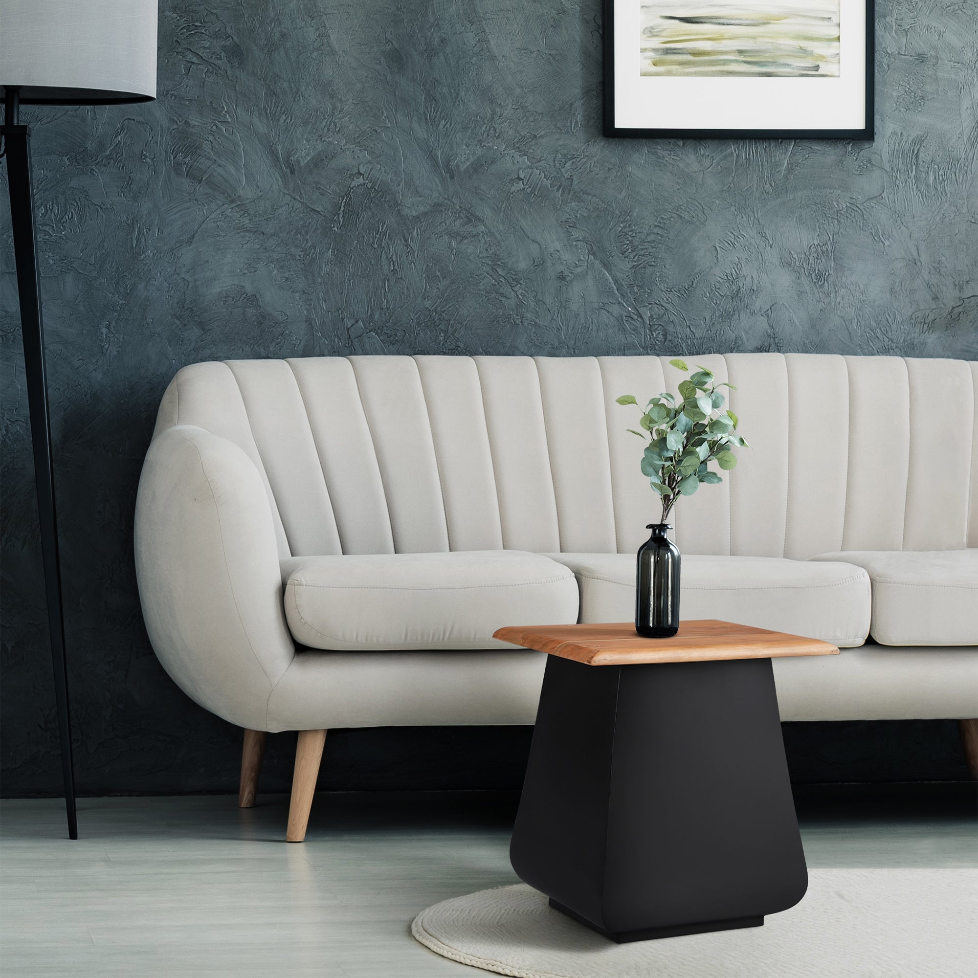 Wohnzimmer mit beigem Sofa, Tisch und Pflanze auf dem Tisch.