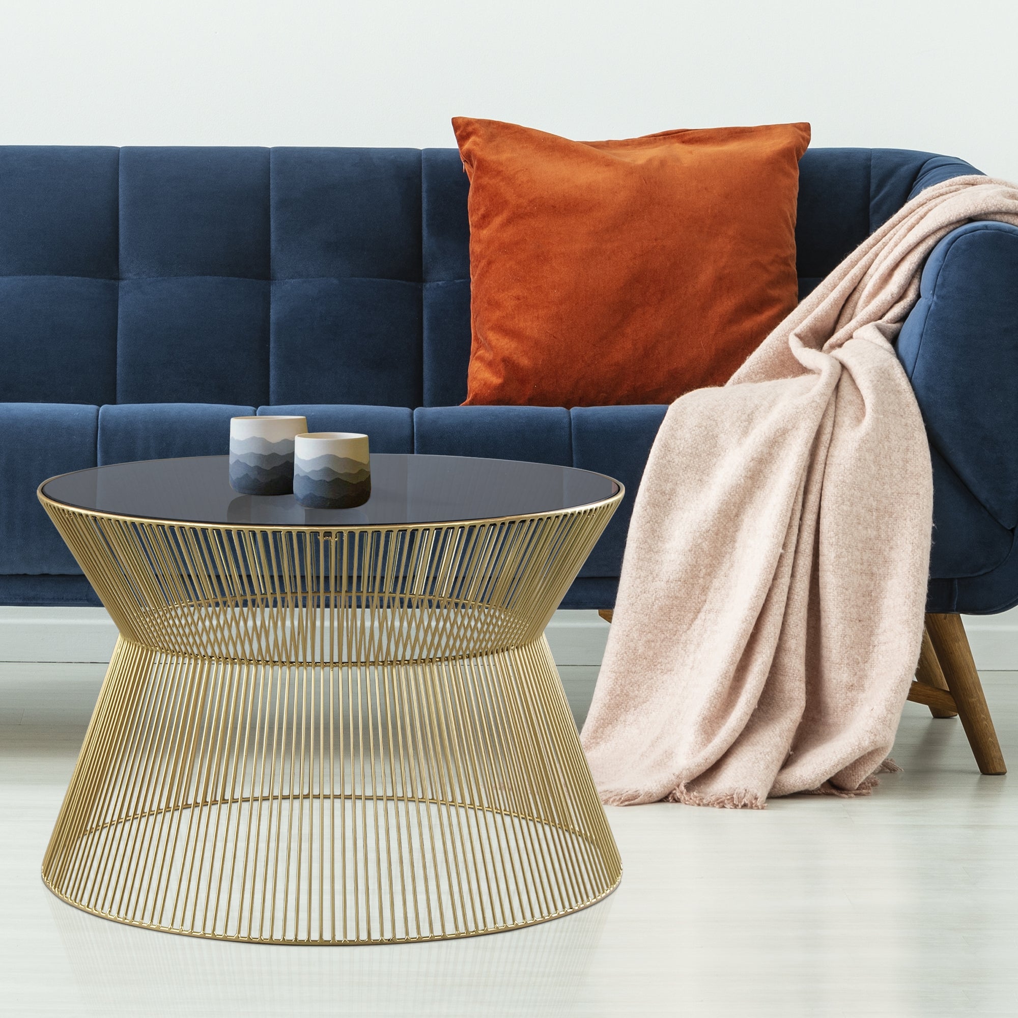 Blauer Sofa mit orangefarbener Kissen, einem runden Tisch und einer Decke.